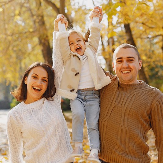 Family with cute little daughter. Father in a brown sweater. Family in a autumn field